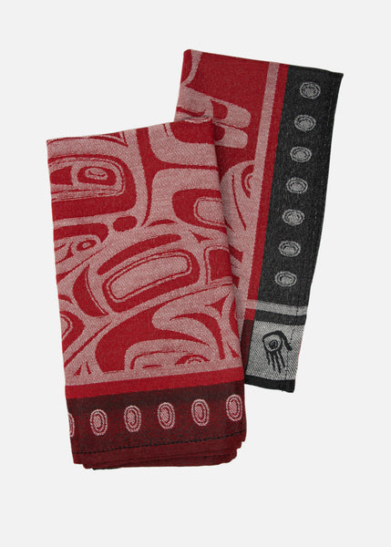 A pair of red jacquard woven napkins with a black dotted border light-red Raven designs. The napkins are folded vertically and slightly overlapping.