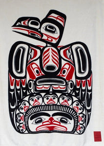 A fluffy blanket printed with a large red and black raven sitting on top of humans and the sun, with white, black, and red fringe.